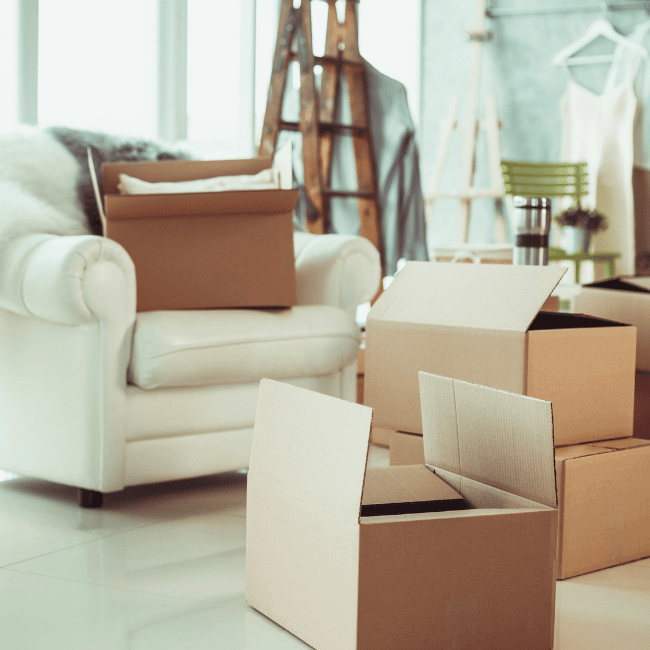 A picture containing indoor, interior with a  couch and boxes being unpacked. It's the house of someone who is selling and buying a home at the same time.
