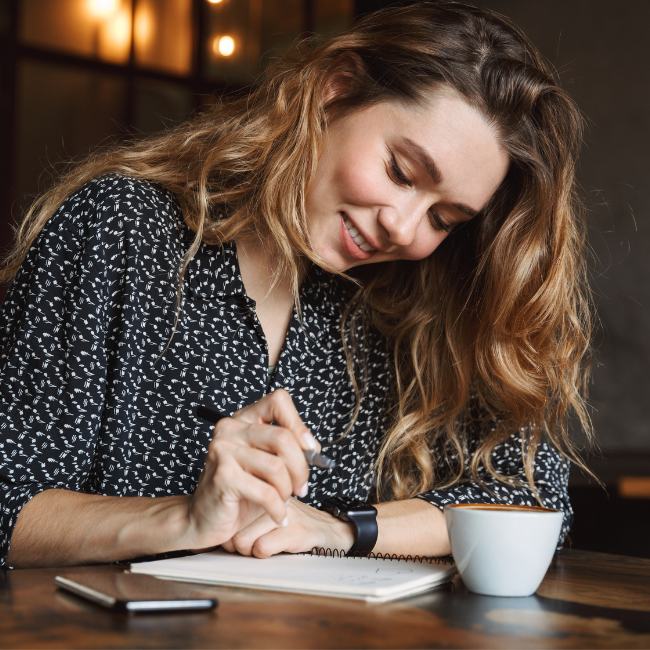 Image of a young brunette woman writing in a notebook as she prepares for her estate planning session