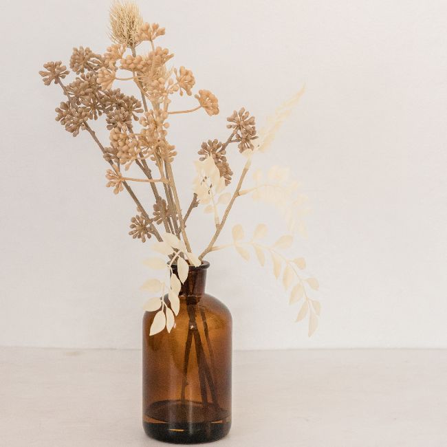 recycled glass bottle with dried flowers in it representing sustainable chic home open styling