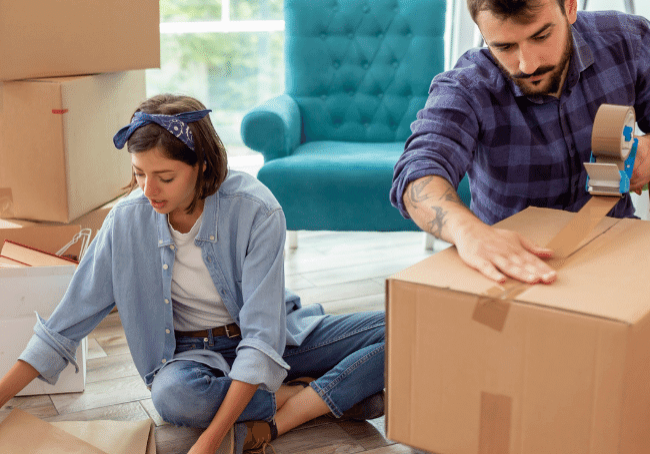 Selling-Your-House-How-to-Emotionally-Prepare image of a couple sitting in the lounge room packing boxes
